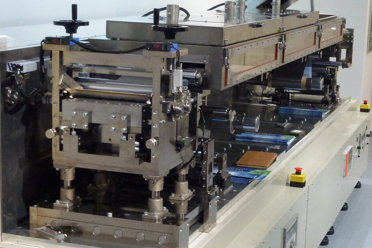 Stainless steel electrode coating machine on a white frame, with its rollers, adjustment knobs and coated electrode sheets