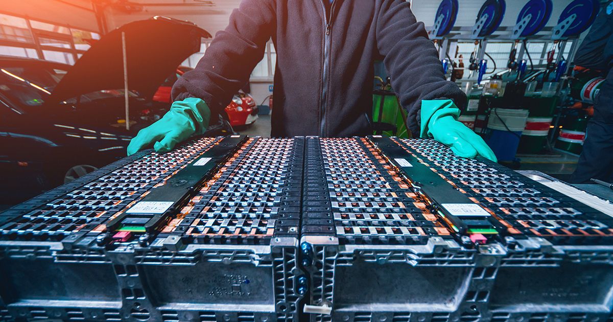 Technician handling lithium-ion battery packs in an assembly workshop