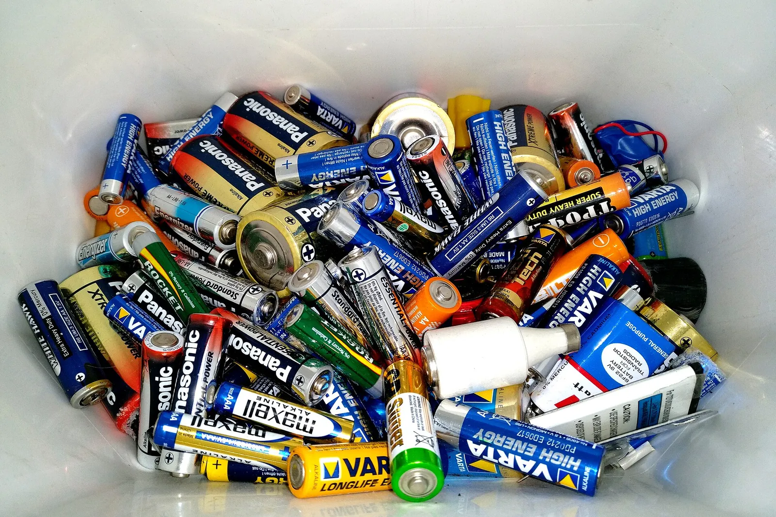 Collection bin filled with used alkaline cells and small batteries from many brands