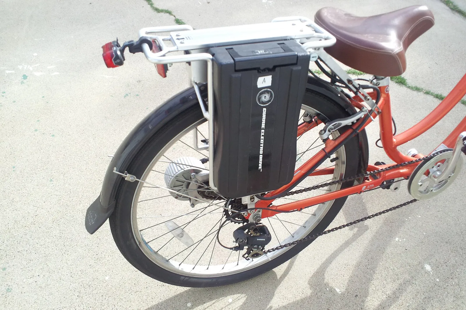 Black e-bike battery attached to the rear luggage rack of a red bicycle