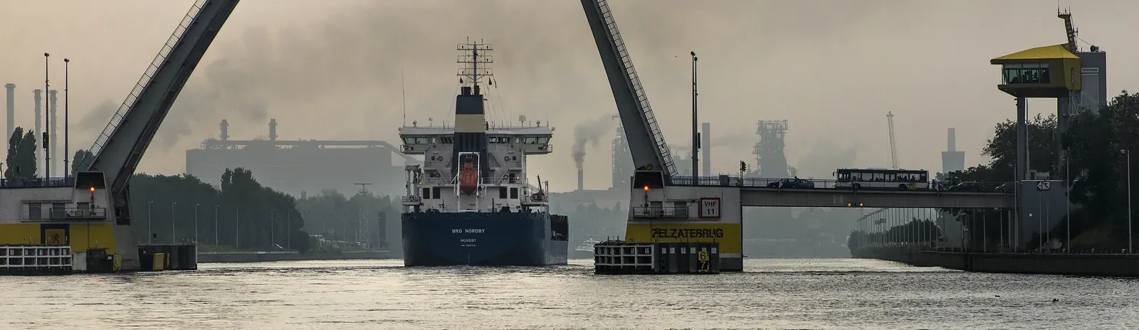 A cargo ship passes through the Zelzate lifting bridge on the Ghent-Terneuzen Canal, with the ArcelorMittal steelworks in the background