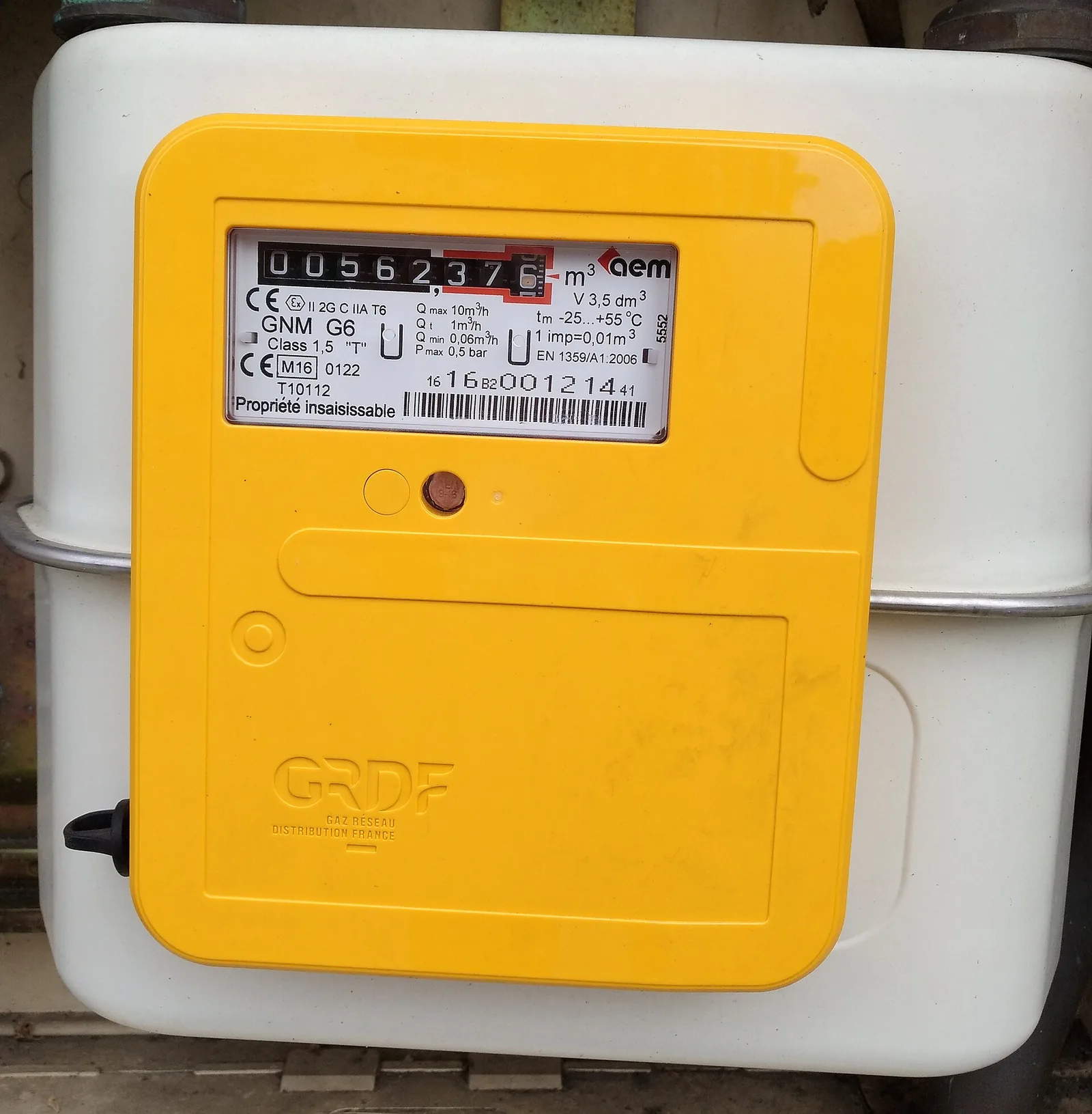 Gas meter with a yellow cover marked GRDF, showing its reading in cubic metres, mounted on a white cabinet