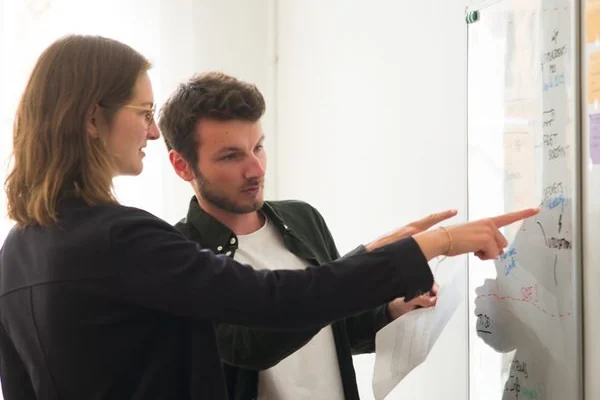 Two members of the Projet Celsius team in front of a whiteboard covered in notes