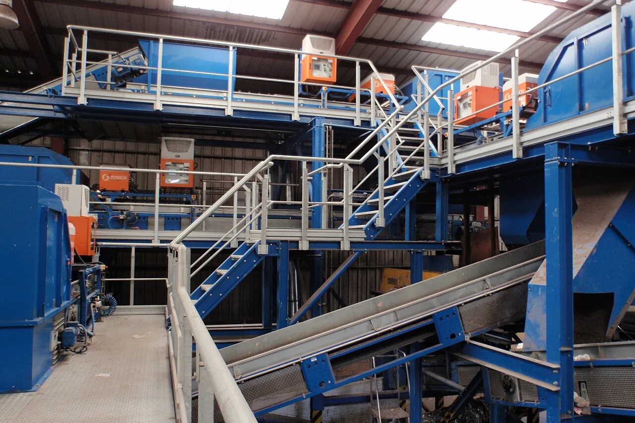 Line of blue optical sorters in a sorting centre, with walkways, stairs and conveyors