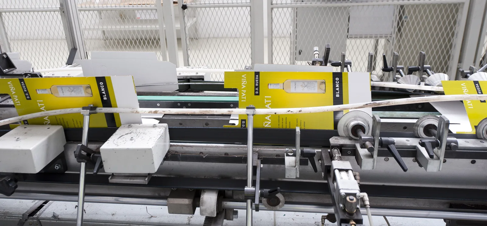 Printed yellow cardboard cartons for a wine bottle, folded and glued in line on a folder-gluer in a packaging factory