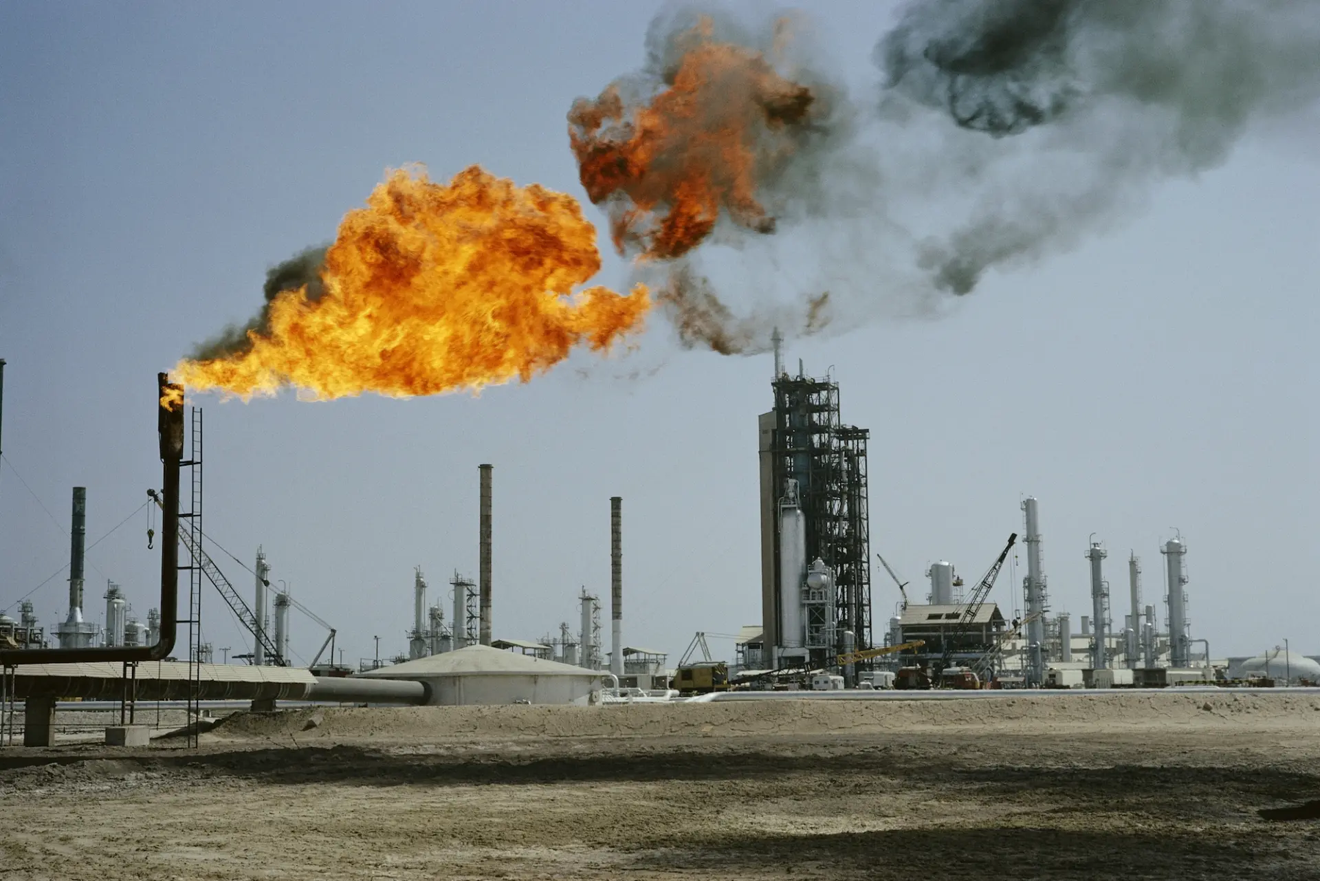 Petrochemical refinery with a gas flare, smoke and a clear sky