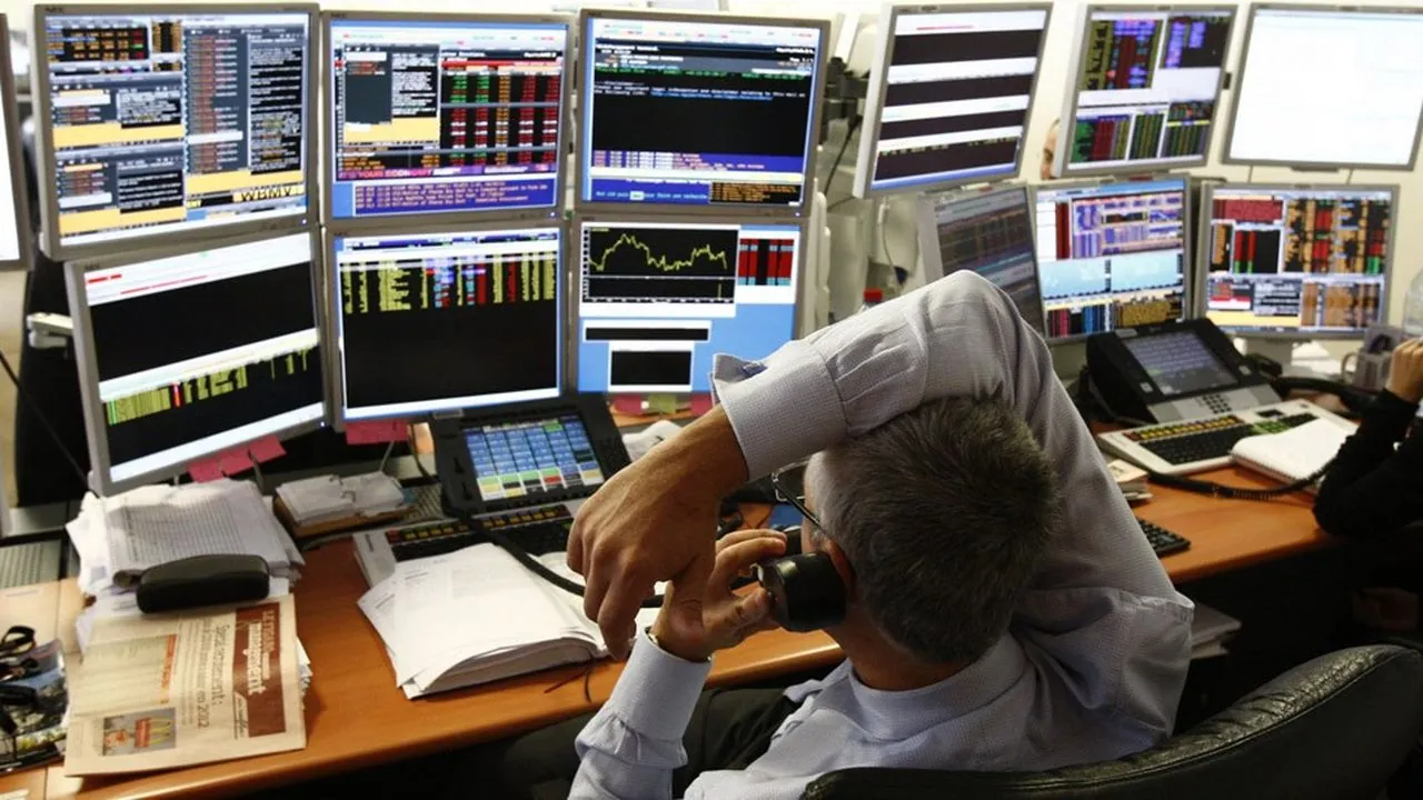 Trader on a trading floor surrounded by screens displaying prices and candlesticks