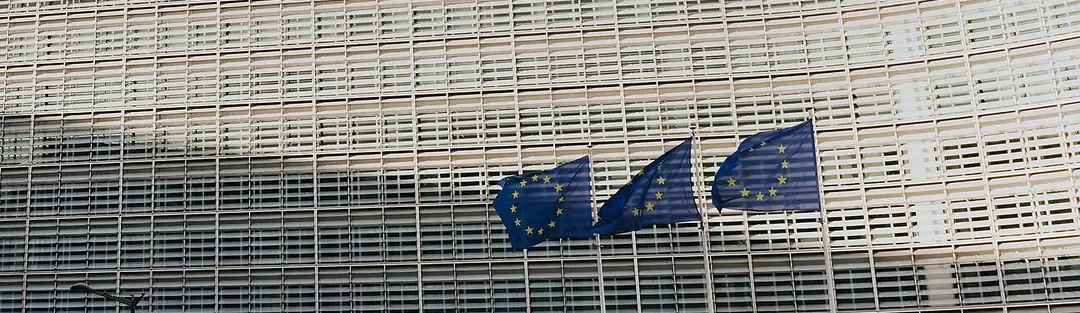 Façade of the Berlaymont building, the European Commission's headquarters in Brussels, with 3 European flags