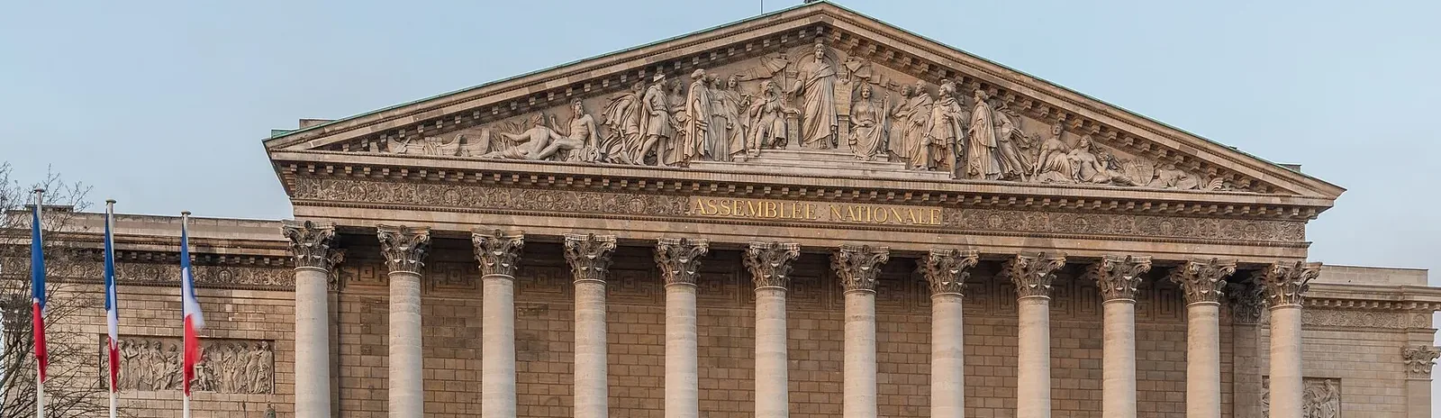 Colonnaded façade of the Palais Bourbon, home to the National Assembly in Paris, under a clear sky