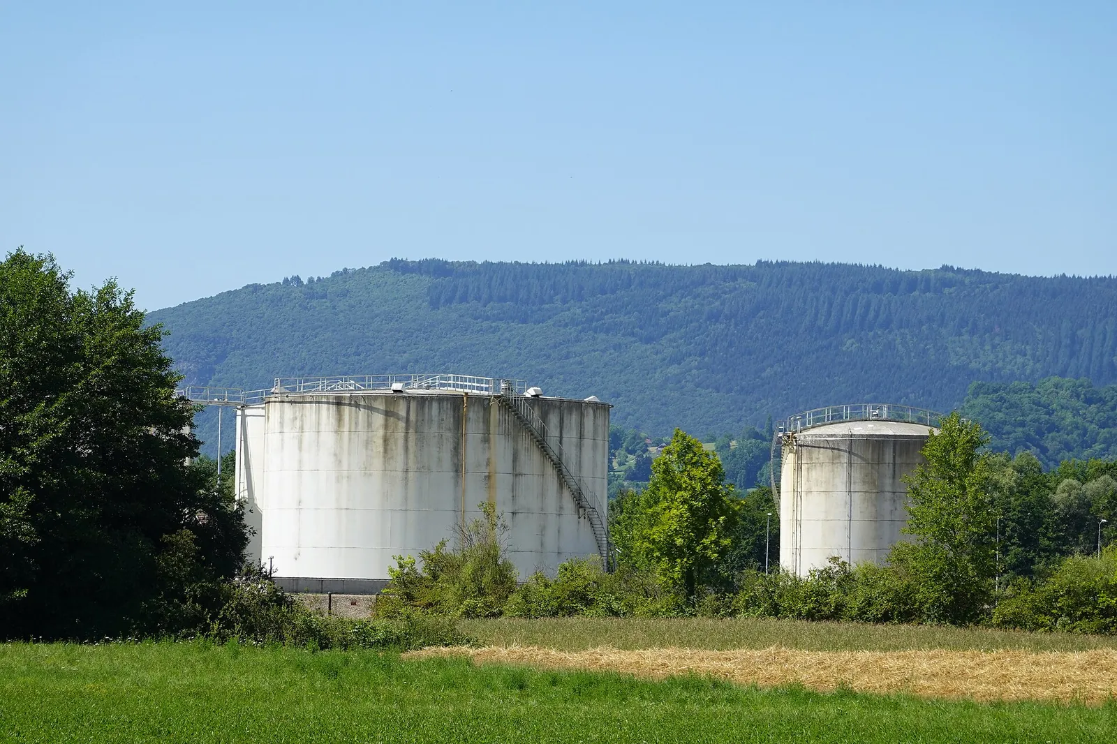 White tank at an oil depot below a wooded hillside in Savoie