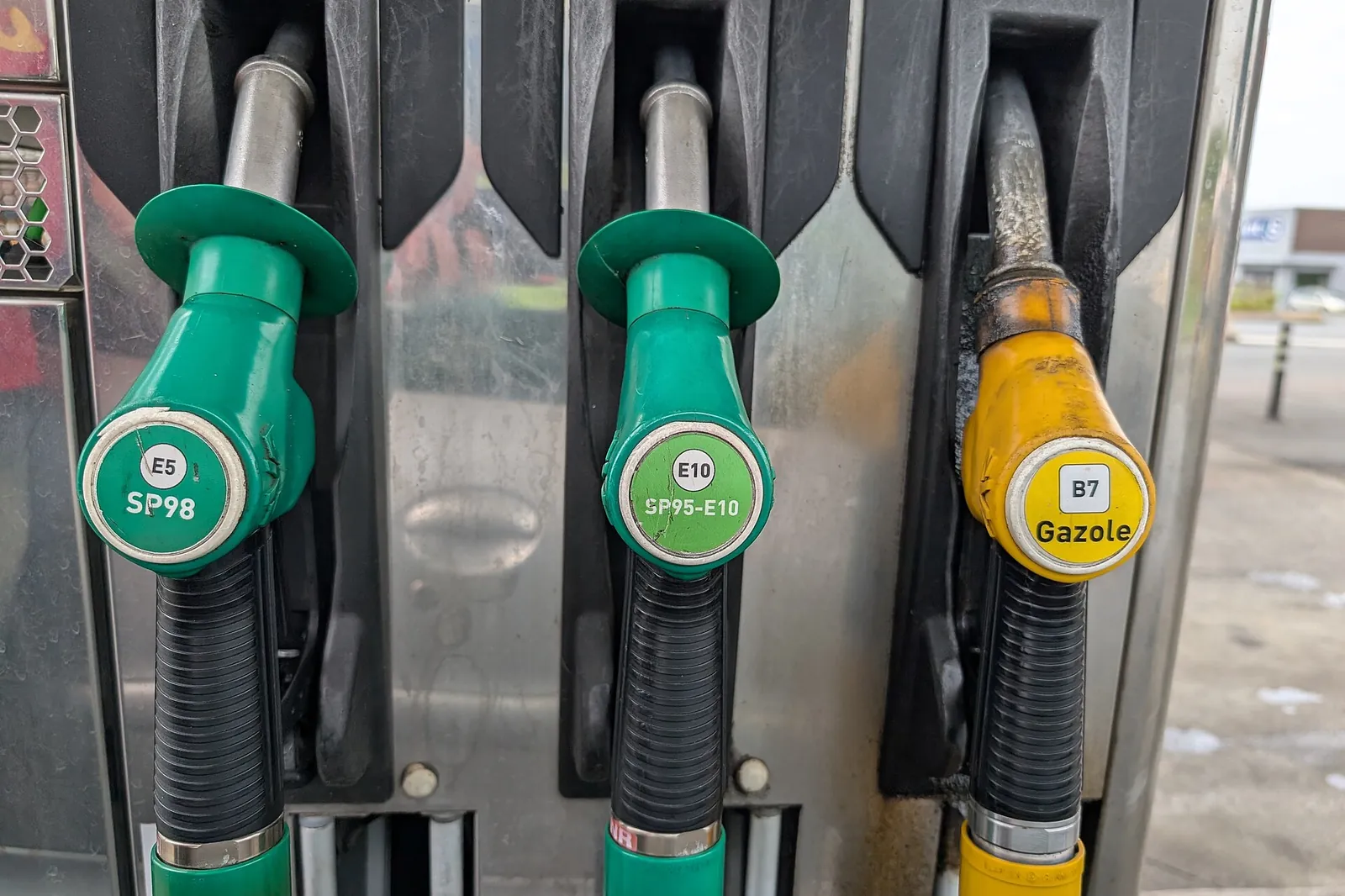 Fuel nozzles side by side at a pump: SP98 E5 and SP95-E10 in green, B7 diesel in yellow