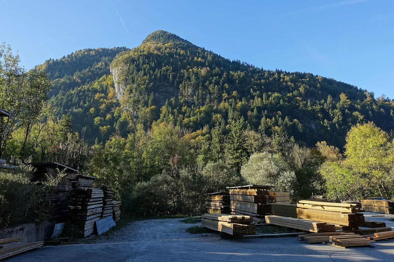 Stacks of sawn timber outside a sawmill in Thônes, at the foot of a wooded mountain