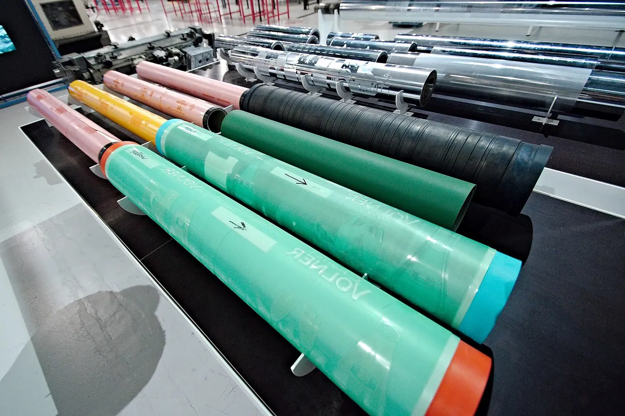 Pink, yellow, green and black printing cylinders and sleeves lined up on a flexographic press