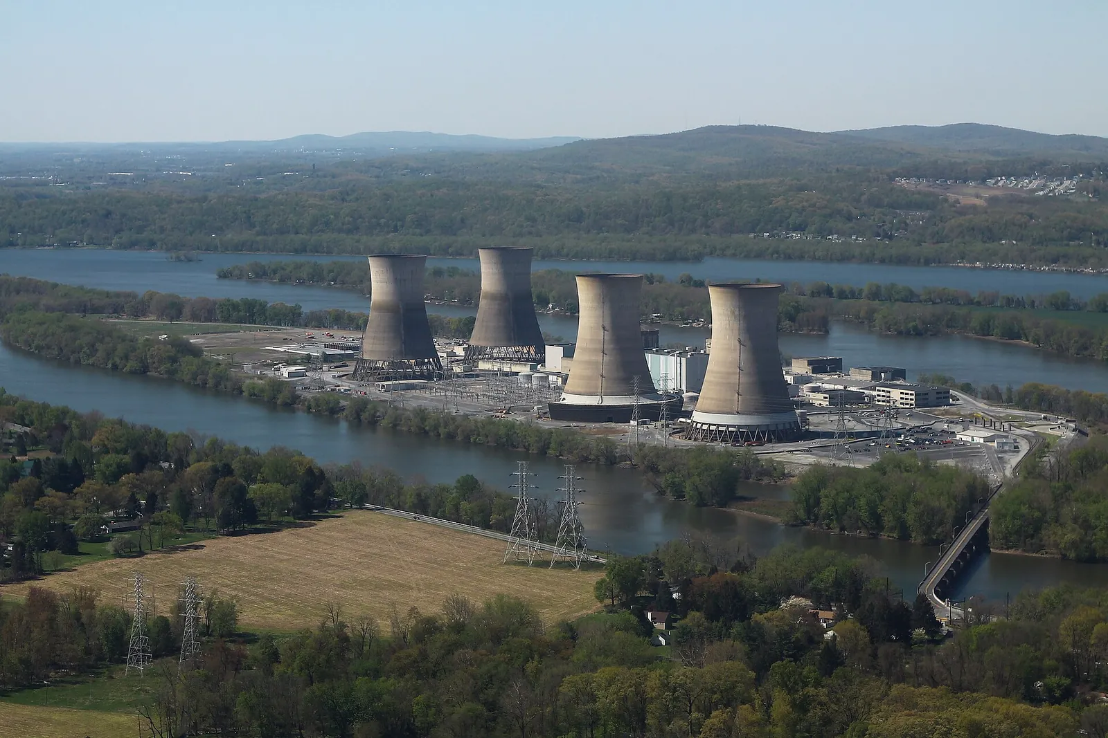 Aerial view of a nuclear power station on a river island, with its 4 cooling towers and electrical substation