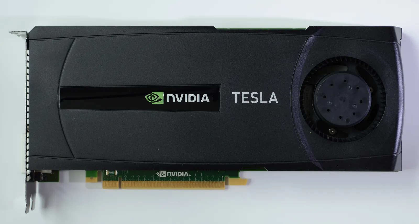 An Nvidia Tesla computing card lying flat on a white background, with its black and green casing