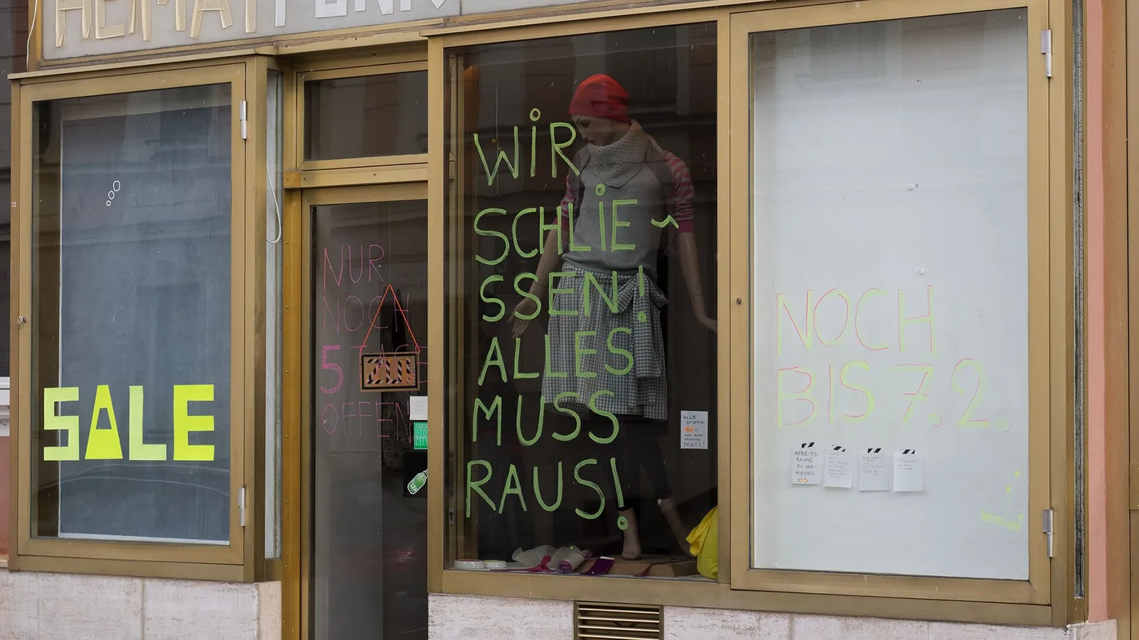 Clothing shop window with a sale poster and a message saying everything must go