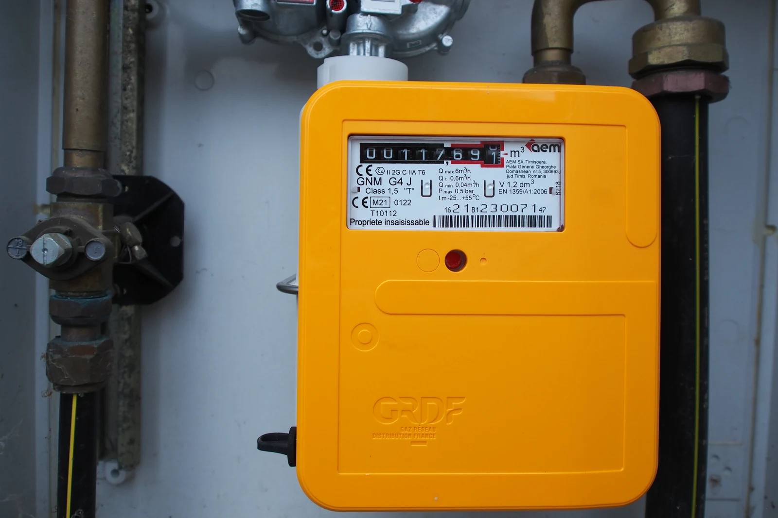 Yellow GRDF Gazpar smart gas meter, connected to its pipework in a cabinet