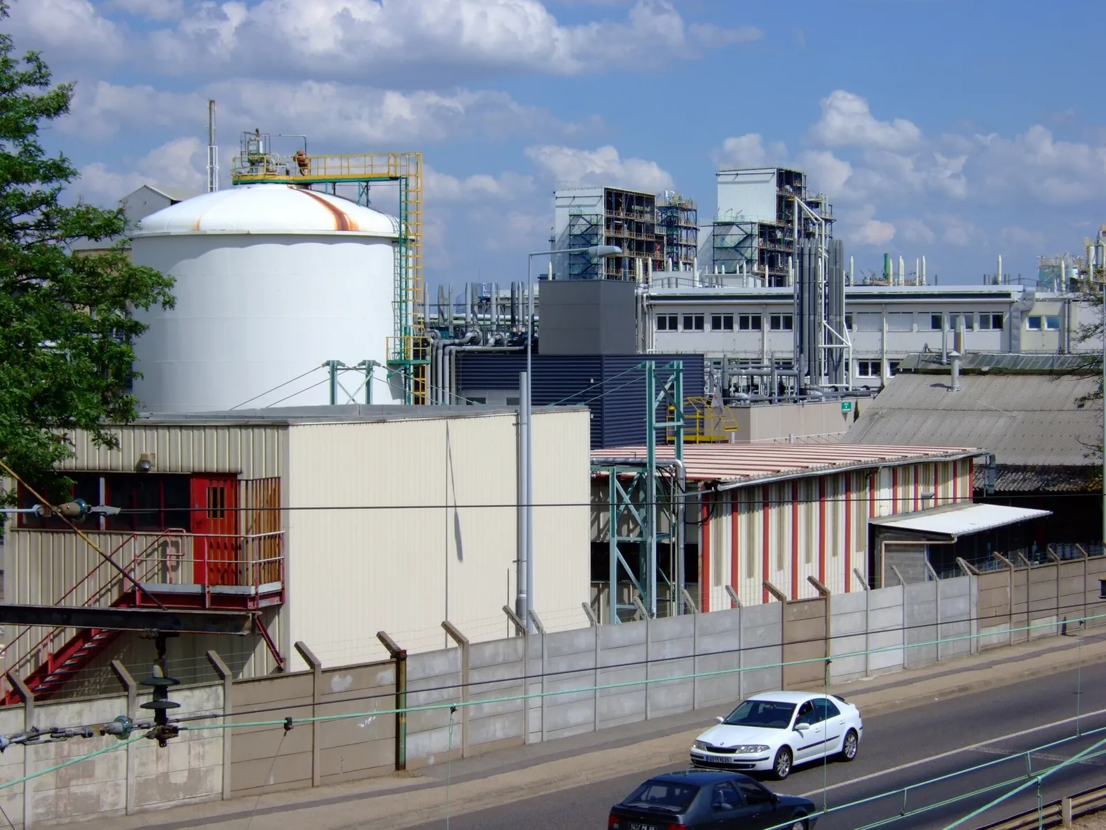 Arkema plant at Pierre-Bénite: a white storage tank and industrial buildings alongside a road