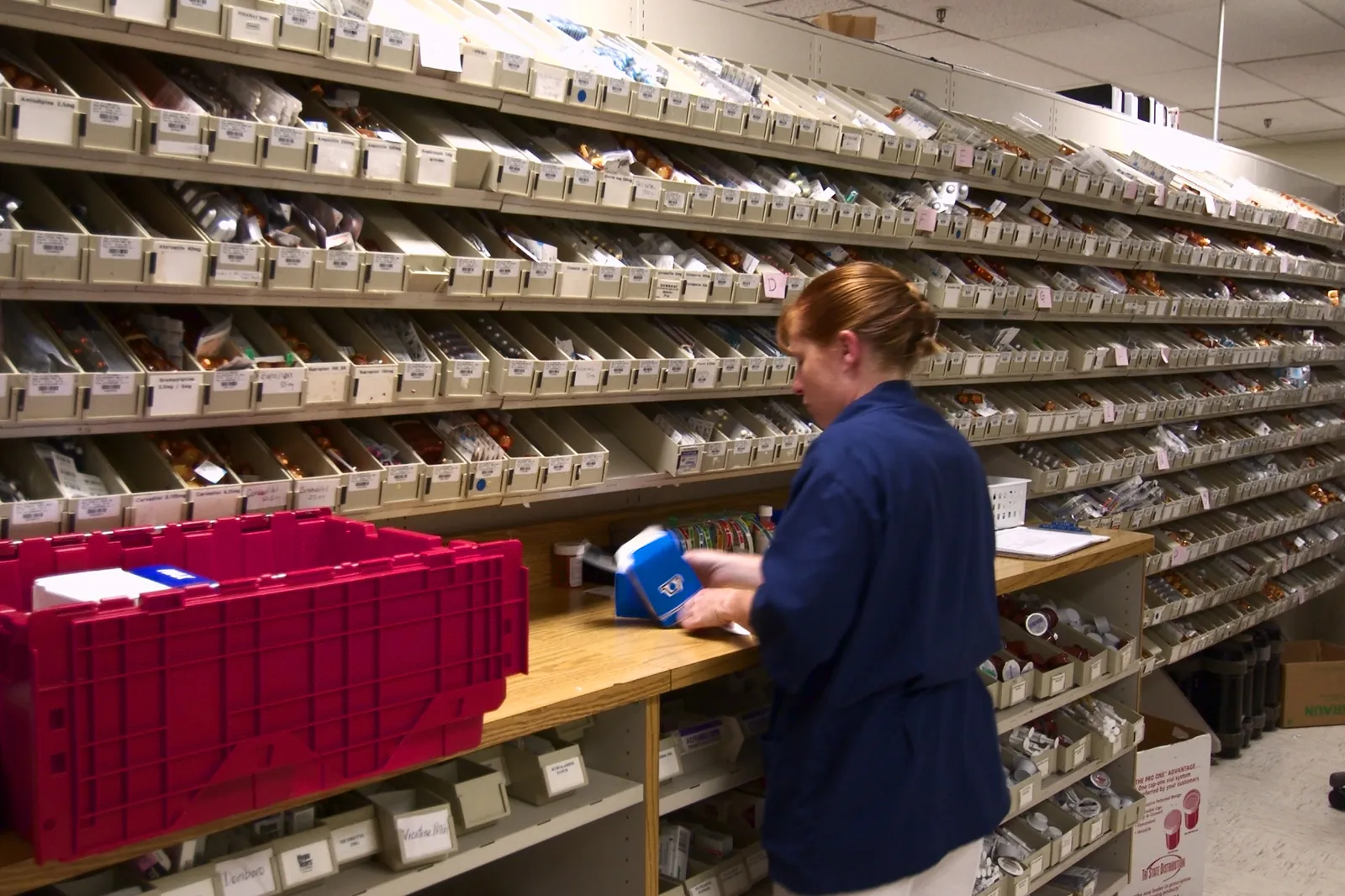 A pharmacy technician unpacks medicine boxes to restock the bins in a hospital pharmacy