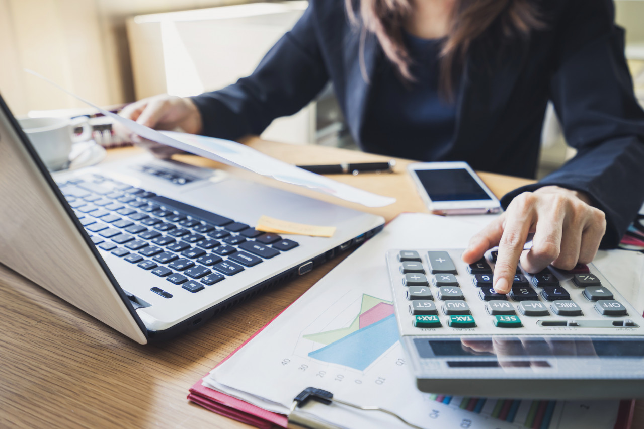 Consultant preparing a Bilan Carbone® budget with a calculator and financial documents