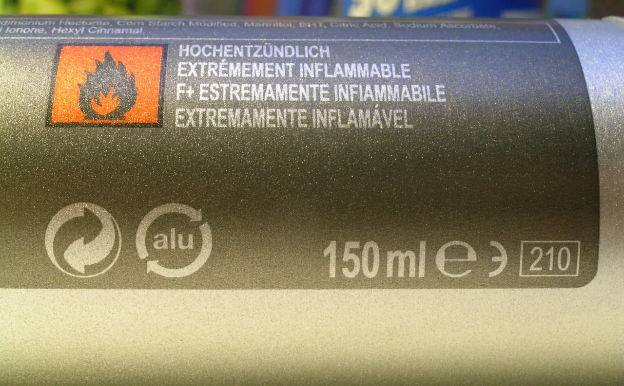 Close-up of a deodorant spray can: orange "extremely flammable" pictogram in 4 languages, the Green Dot, the "alu" symbol and the 150 ml capacity