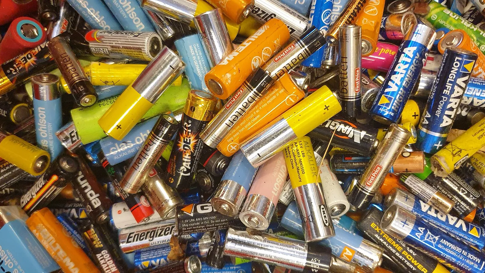 Heap of used alkaline batteries of various brands and sizes