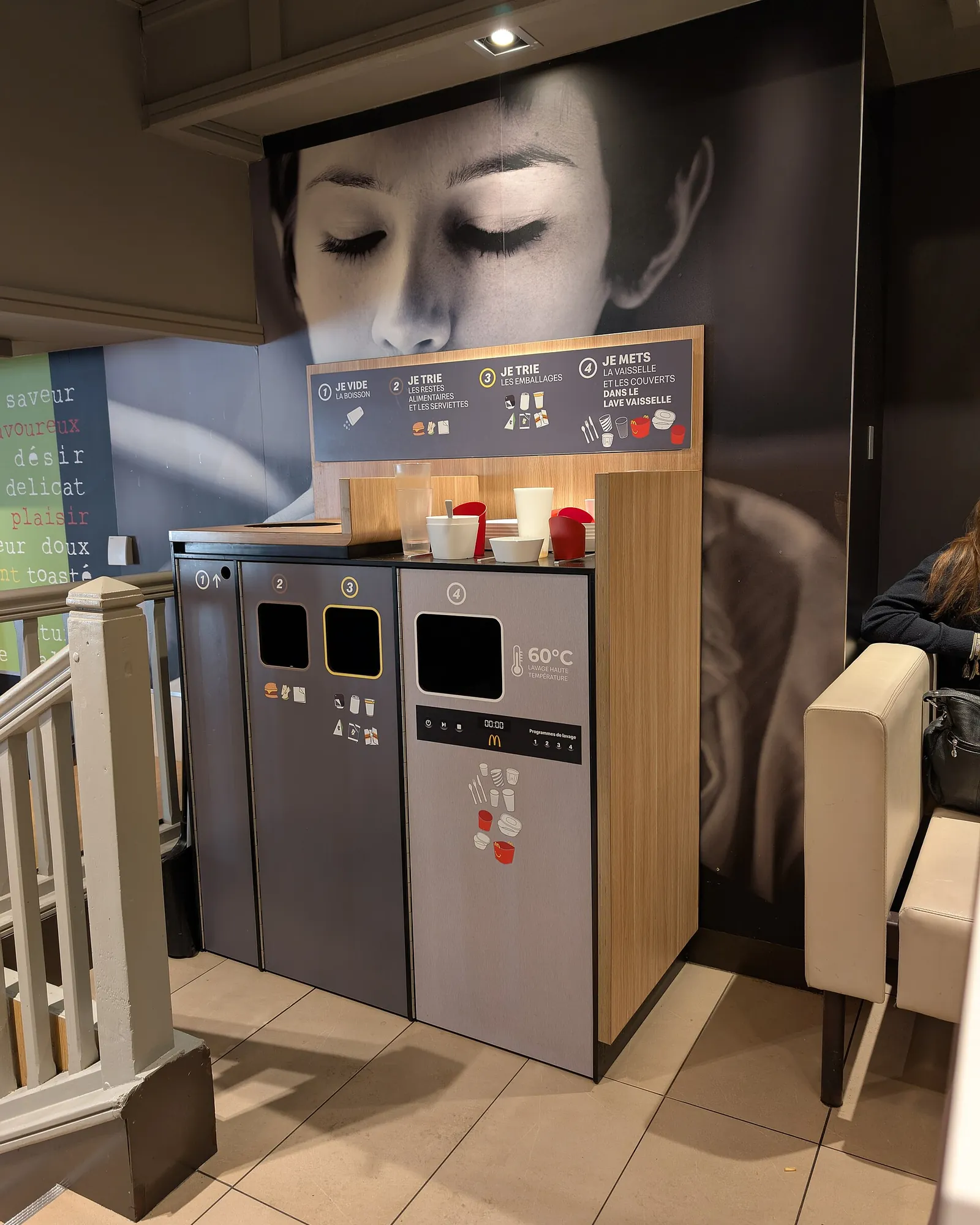 Sorting unit with several bins in the dining room of a fast-food restaurant in Caen, beneath a poster
