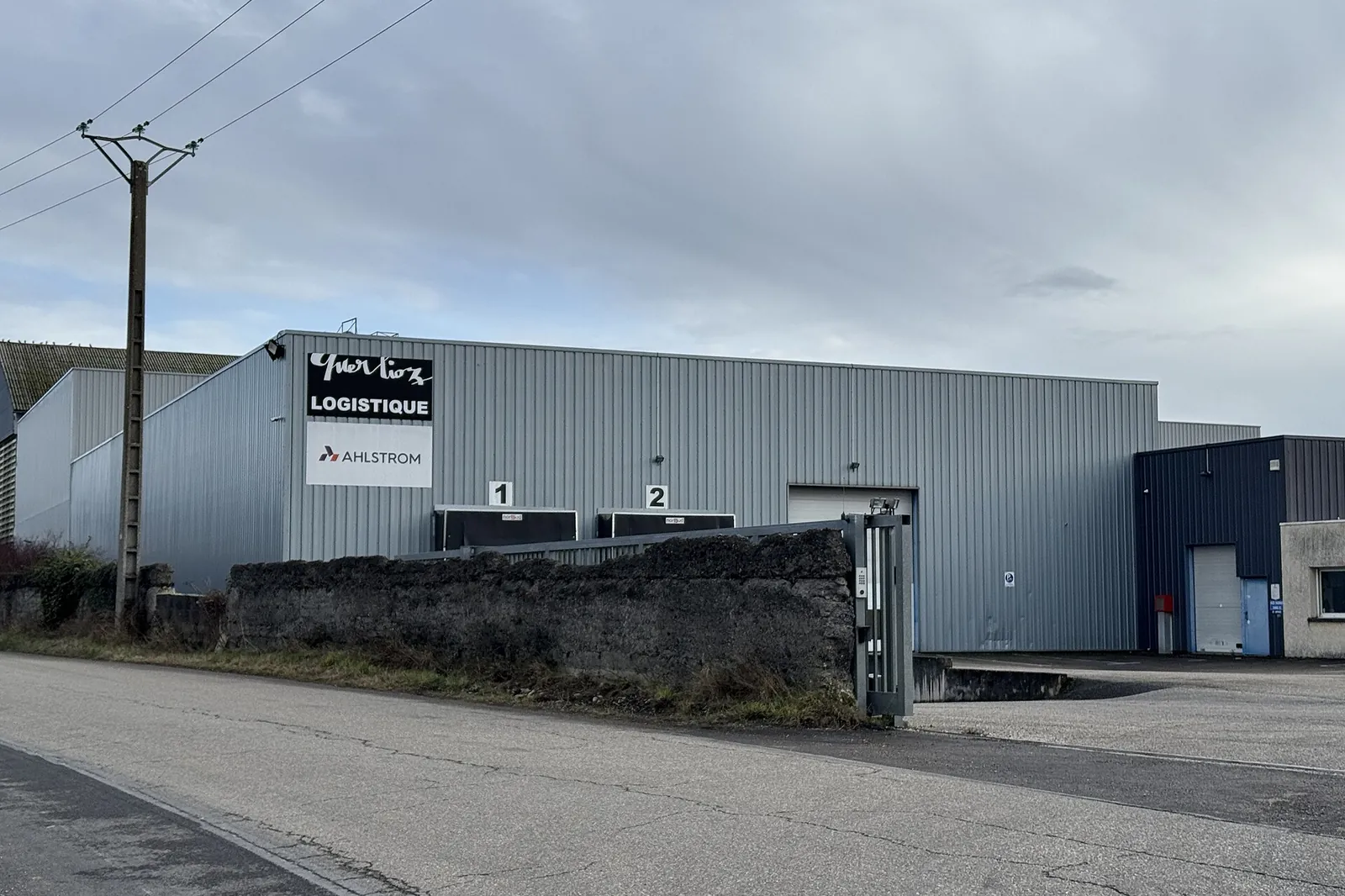 Metal-clad logistics warehouse with loading bays, on the outskirts of a town in Isère