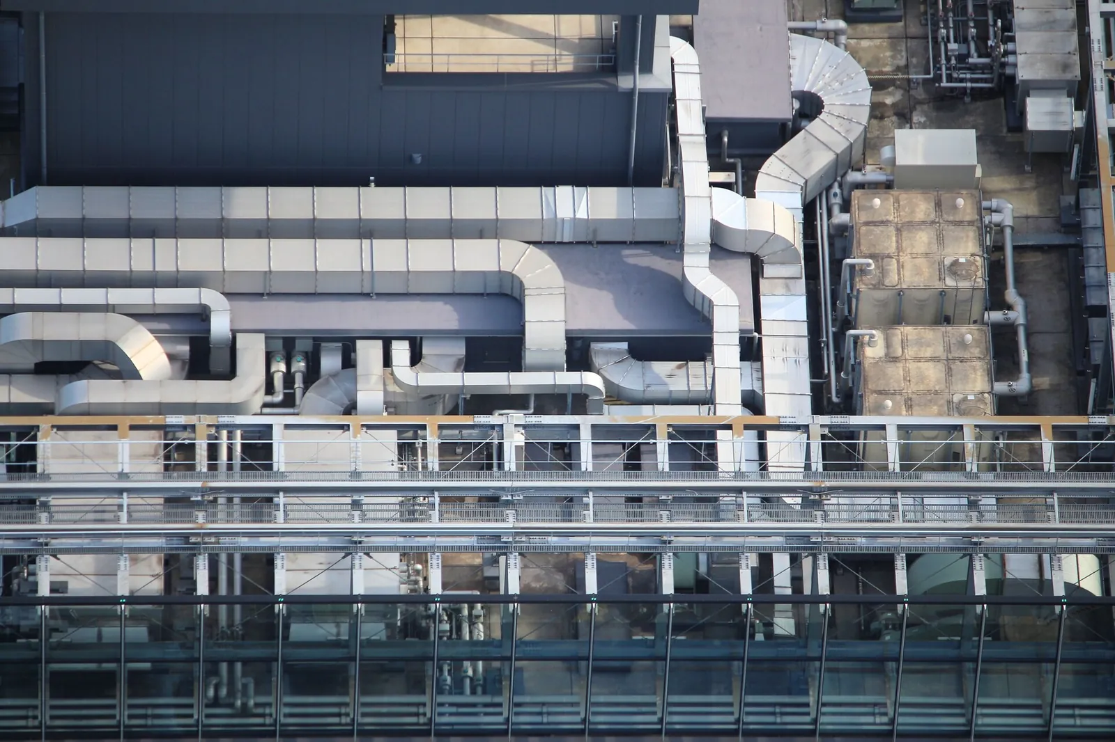 Building roof covered with air-conditioning units, ventilation ducts and metal walkways