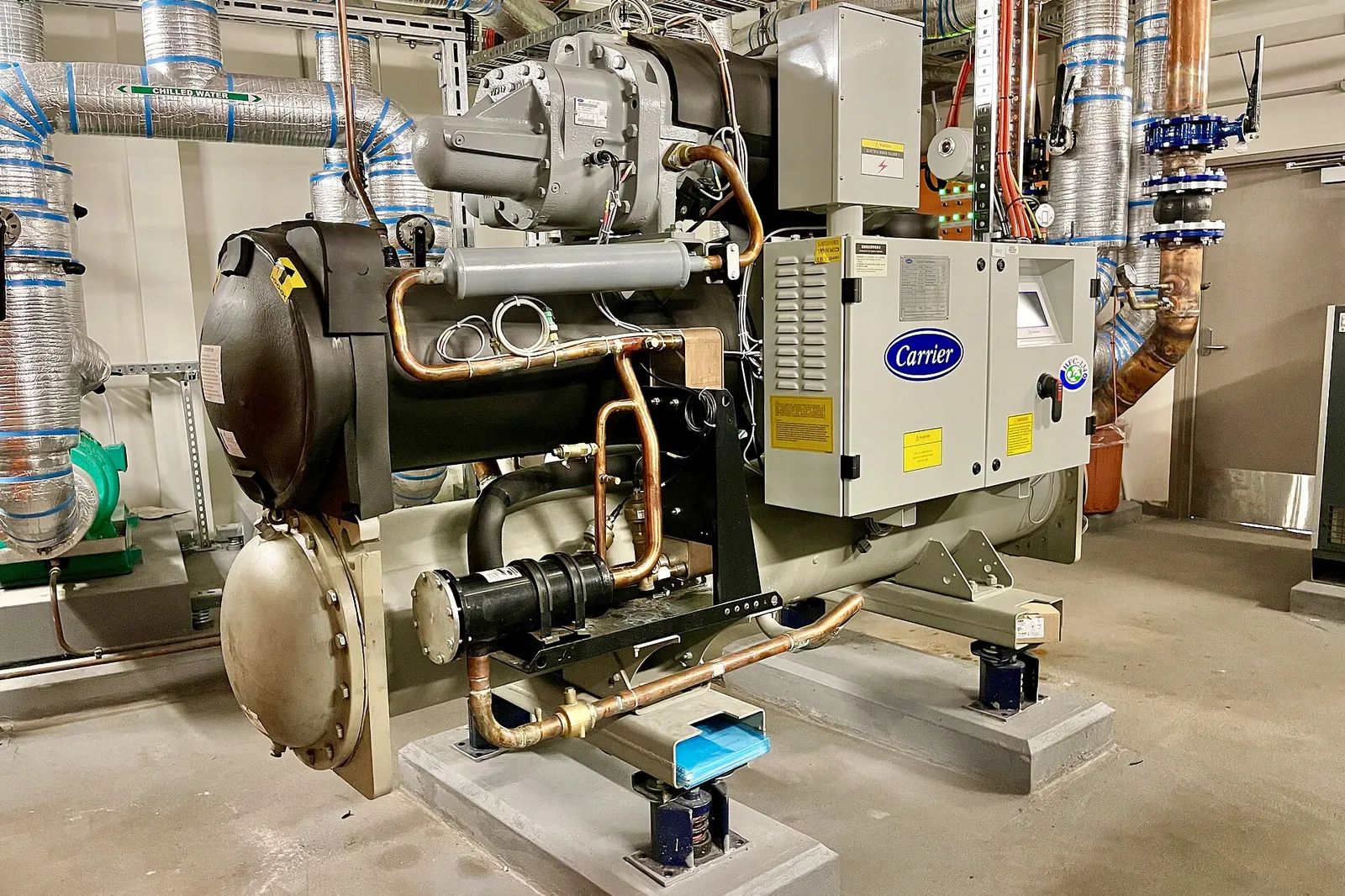 Chilled-water plant in the plant room of a large tertiary building, surrounded by insulated pipes